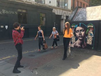 People on street against buildings in city