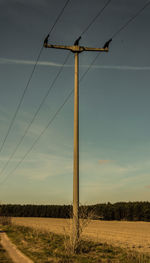 Electricity pylon on field against sky