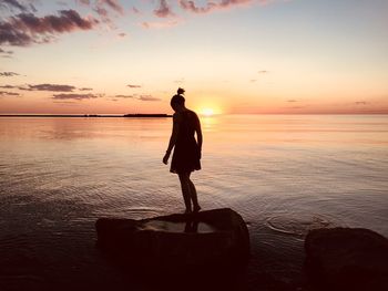Silhouette man standing on beach against sky during sunset