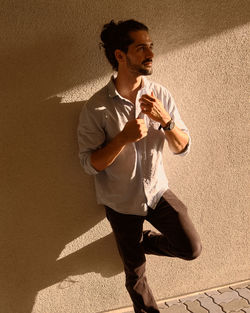 Full length of young man standing against wall