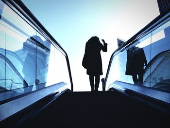 Low angle view of woman on escalator against sky