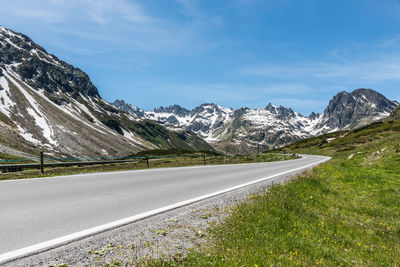 Road by mountains against sky