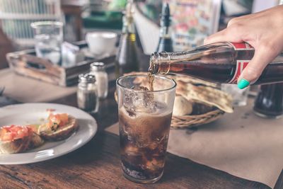 Cropped image of person holding drink on table