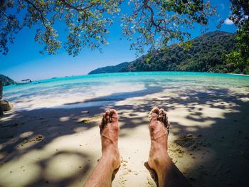 Low section of man relaxing at beach