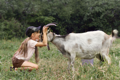Side view of woman with goat on field