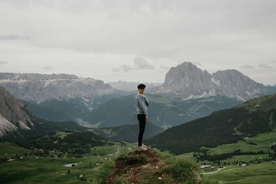 Woman standing on top of the rock overlooking the mountains