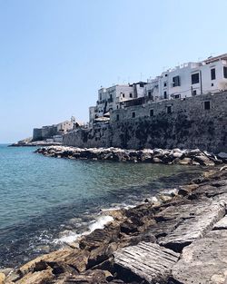 Scenic view of sea by buildings against clear sky