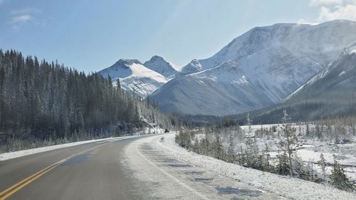 Road amidst snowcapped mountains against sky