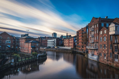 Canal amidst buildings against sky at dusk