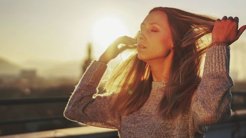 Young woman looking away while standing against sky