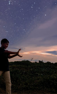 Man standing on field against sky during sunset