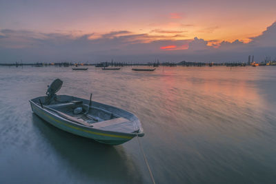 Boat moored at beach against sky during sunset
