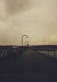 Railing by water against sky during sunset