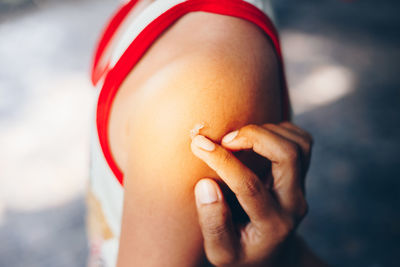 Cropped hand applying cream on shoulder