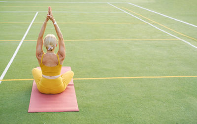 Rear view of woman exercising on field