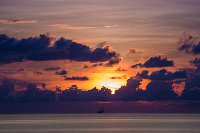 Silhouette trees by sea against sky during sunset