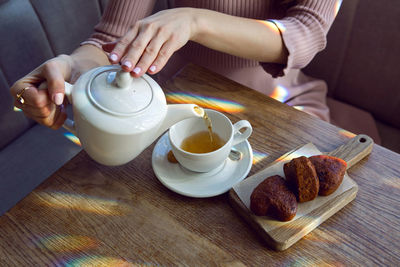 Girl sitting at a table in a restaurant with tea and cookies in the form of hearts