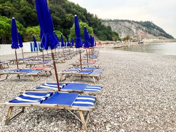 Empty chairs on beach against blue sky