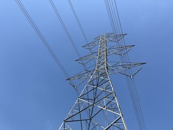 Low angle view of electricity pylon against blue sky