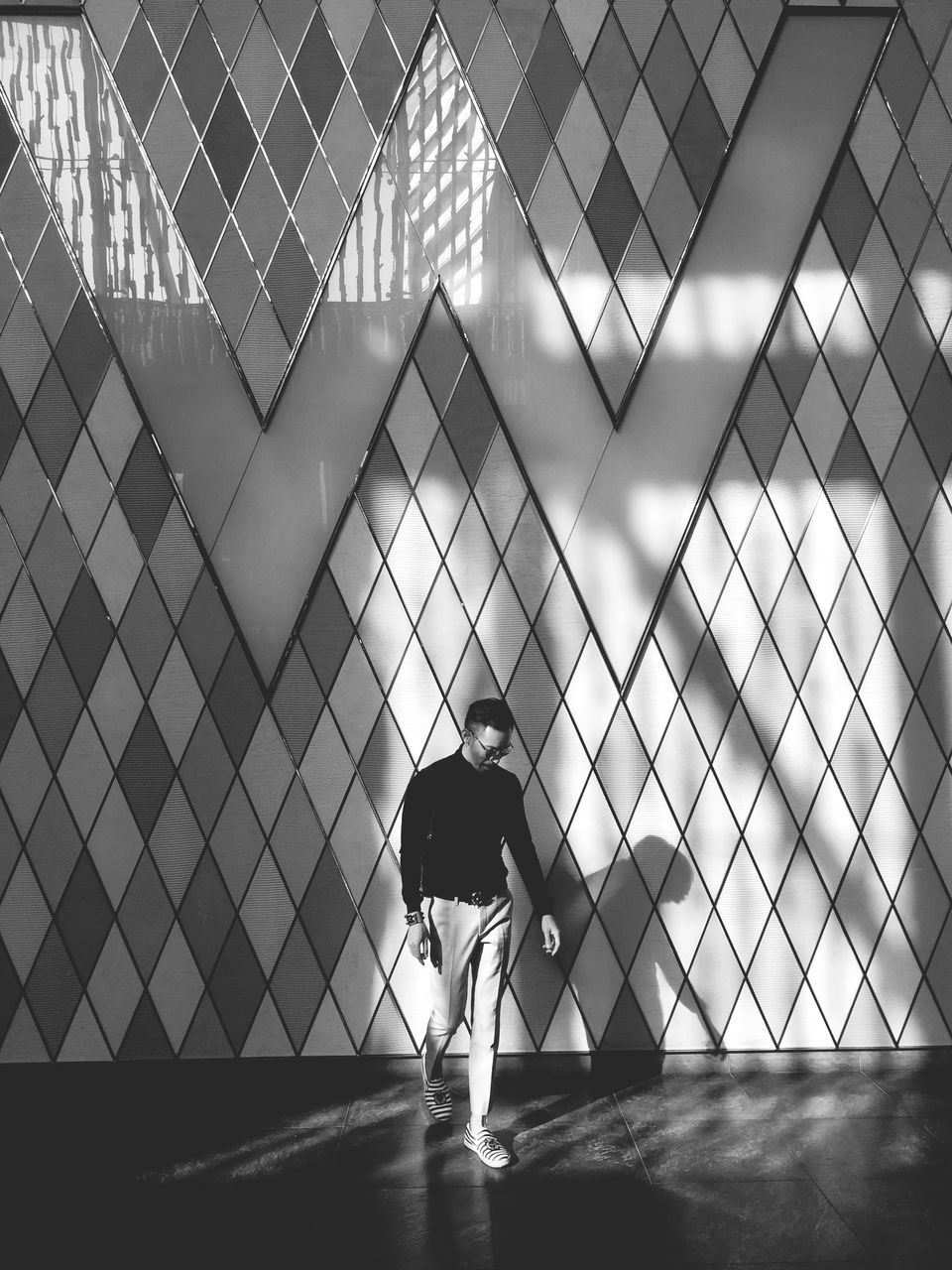 indoors, lifestyles, glass - material, leisure activity, full length, standing, men, reflection, transparent, window, architecture, rear view, person, built structure, walking, modern, pattern, glass