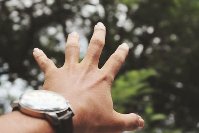 Cropped hand of man wearing wristwatch gesturing outdoors
