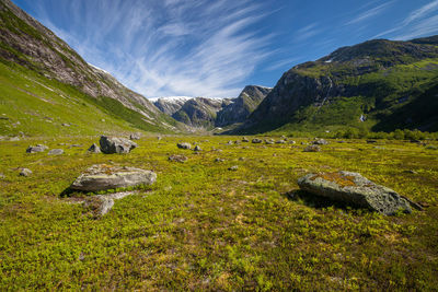 Idyllic shot of green landscape and mountains against sky