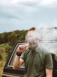 Full length of man holding electric cigarette against sky