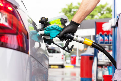 Cropped hand of worker refueling car at fuel pump