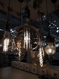 Low angle view of illuminated light bulbs hanging on ceiling