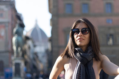 Portrait of woman smiling with sunglasses unfocused background at florence, italy. 50mm lens