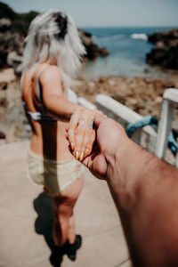 A couple on the beach walk hand in hand. perspective from the man's arm