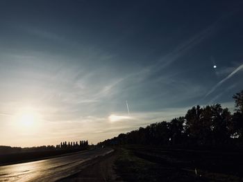 Road amidst silhouette landscape against sky during sunset