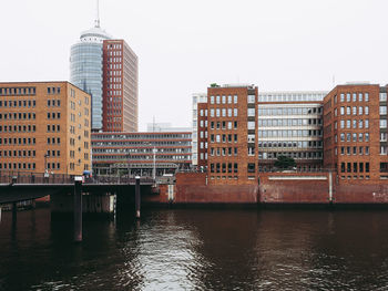 Buildings by river against clear sky