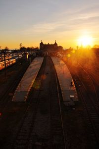 Railroad tracks in city against sky during sunset