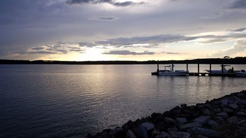 Silhouette of boats in sea against cloudy sky