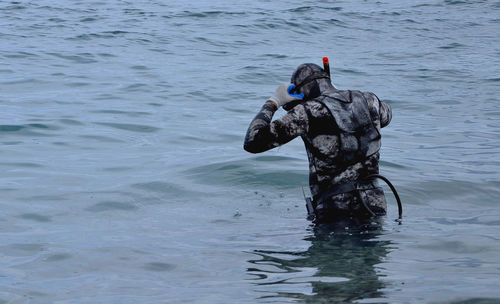 Rear view of diver standing in sea