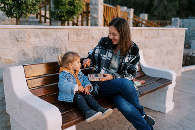 Young woman using mobile phone while sitting on bench