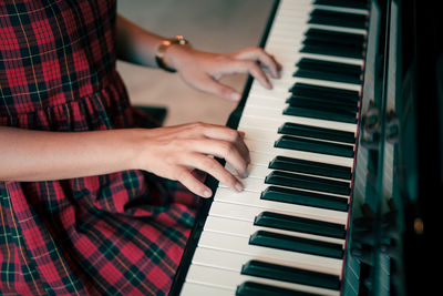 Midsection of young woman playing piano