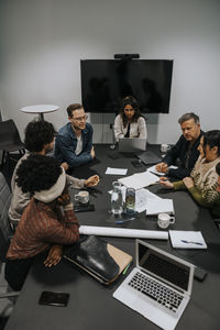 High angle view of multiracial male and female colleagues discussing strategy in board room