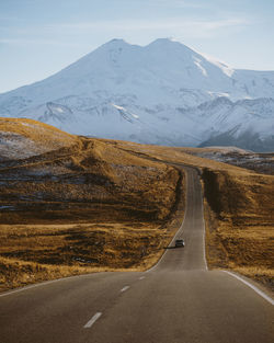 Empty road leading towards snowcapped mountains