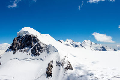 Low angle view of snowcapped mountains against blue sky