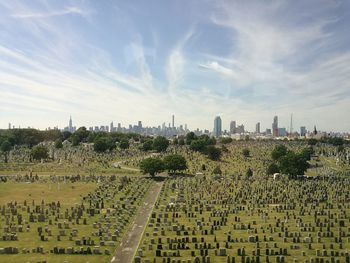 Cemetery by city skyline against sky