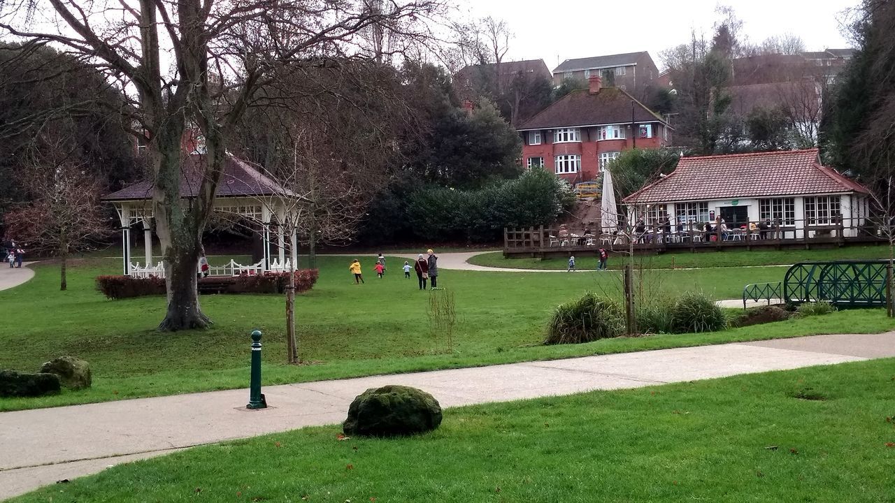 PEOPLE ON FOOTPATH IN PARK BY BUILDINGS