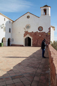 Rear view of man walking outside temple against building