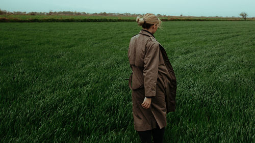 Rear view of woman walking on green land