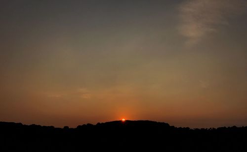 Silhouette trees on field against sky at sunset