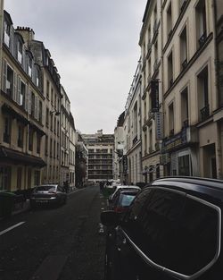 Cars on city street against sky