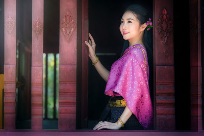 Woman looking away while standing against wall