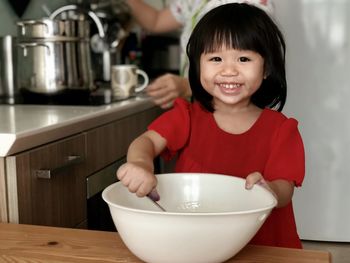 Portrait of cute little girl cooking at home