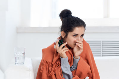 Ill woman taking medicine while sitting at home